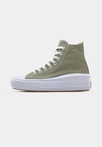 Sneaker alta in tela verde chiaro con lacci bianchi, punta in gomma bianca e suola piatta bianca spessa. Design minimalista.