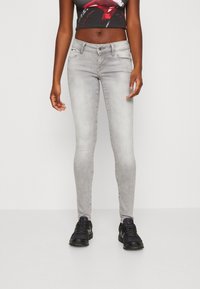 Tunna grå denimjeans med framfickor, medelhög midja och lätt slitningar. Matchas med svarta sneakers.