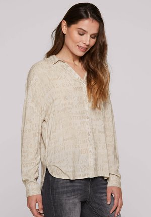 Beige, knöpfbares Hemd mit handgeschriebenem Textmuster. Verfügt über einen Kragen, lange Ärmel und einen leicht abgerundeten Saum. Weicher Stoff, lässige Passform.