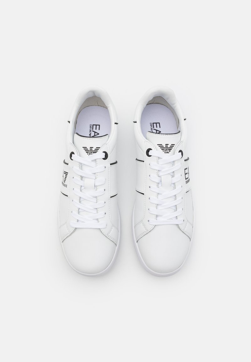 Weiße Turnschuhe mit einem glatten synthetischen Obermaterial, schwarzen horizontalen Streifen und markanten Akzenten. Klassische Schnürung und rundes Zehendesign.