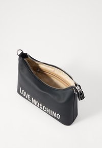 Μαύρη τσάντα με φερμουάρ, κατασκευασμένη από λείο υλικό, με την επιγραφή "LOVE MOSCHINO" σε έντονα λευκά γράμματα, εσωτερικό σε ανοιχτό χρώμα και ασημί αξεσουάρ.