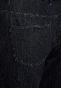 Vaqueros de mezclilla negra, con una textura suave, bolsillos traseros estándar con detalles de costura y un diseño ajustado.