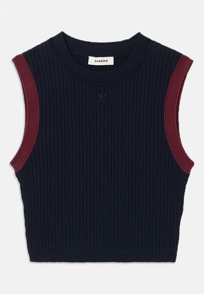 Tumšo jūras zilo krāsu riboto bez piedurknēm topu ar bordo akcentiem uz pleciem. Iezīmējas ar apaļu dekoltē un logo detaļu centrā.