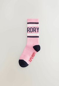 Różowa skarpetka do kostki z granatowymi akcentami, z prążkowanym ściągaczem i wyraźnym logo "SUPERDRY". Wzmocniony palec i pięta dla większej trwałości.