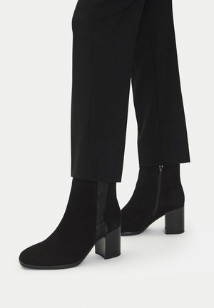 Czarne zamszowe botki na słupku, z elastycznymi panelami po bokach i bocznym zamkiem. Gładka faktura i zaokrąglony kształt noska.