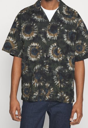 Camisa de manga corta con una tela verde oscuro y un patrón de girasoles en tonos marrones, blancos y azules. Tiene un cuello tradicional y cierre de botones al frente.
