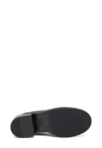 Scarpa di pelle nera con una suola in gomma piatta e texturizzata. Accentatura con tacco curvo e tomaia liscia. Design minimalista, senza branding visibile.