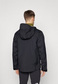 Chaqueta impermeable negra con capucha, que presenta una textura suave, puños elásticos y un corte relajado. La vista trasera muestra un diseño simple sin logotipos.