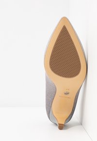 Chaussure grise à bout pointu avec une tige en tissu texturé, un talon fin et une semelle plate en caoutchouc dotée d'un motif antidérapant. Taille 37 indiquée sur la semelle.