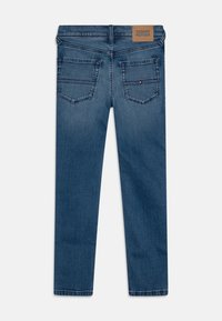 Niebieskie dżinsy typu straight leg, z dwiema tylnymi kieszeniami, wyblakłą fakturą i brązową skórzaną metką na pasku.