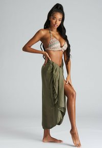 Top bikini con motivo zigzag multicolore e collo halter; gonna avvolgente verde oliva con bordi sfilacciati lasciata cadere in vita.