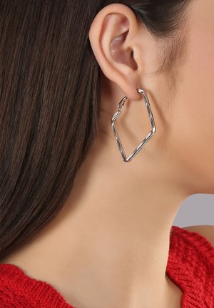 Silberner geometrischer Creolenohrring in einer angularen Form mit einem gedrehten Design. Leichtes Metall mit glänzender Oberfläche, sichert mit einem Hakenverschluss.