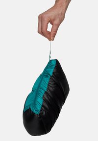 Sorte komprimerbar taske med teal detaljer, der har en lynlåslukning og et slankt design, der bliver holdt af en hånd. Glat, let tekstur.