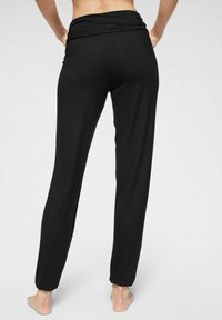 Zwarte, taps toelopende broek met een zachte, brede tailleband. Stevige textuur, met enkelmanchetten. Geschikt voor casual of relaxte outfits.
