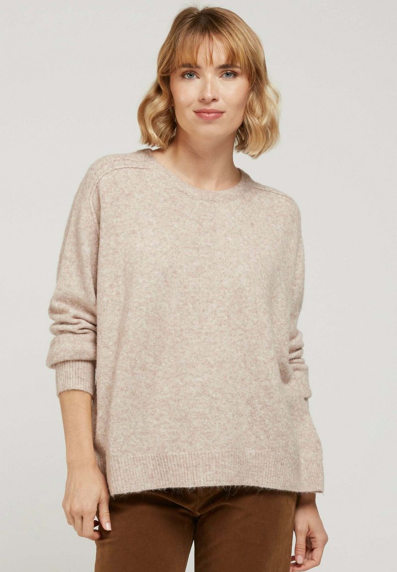 Pull léger rose en maille douce. Il présente un col rond, des épaules tombantes, et des poignets côtelés avec une coupe décontractée.