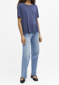 T-shirt a maniche corte blu navale in tessuto morbido, abbinato a jeans dritti blu chiaro e scarpe nere in vernice a punta quadrata.