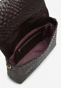 Sac à main en cuir tressé marron foncé avec rabat ouvert, dévoilant un intérieur en tissu violet et une poche intérieure zippée.