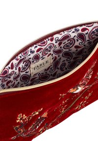 Rood fluwelen clutch tas met bloemenborduursel. Interieur heeft een paisley-print voering en een stoffen label. Gouden ritsdetail.