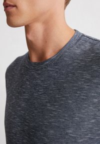 Grau gestreiftes T-Shirt mit rundem Halsausschnitt. Der Stoff hat eine weiche Textur und zeigt subtile Farb- und Mustervariationen auf der Oberfläche.