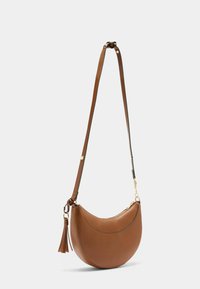Bolso de cuero marrón tipo bandolera con forma curvada, herrajes dorados y un detalle de borla. Cuenta con una correa ajustable y textura suave.