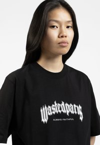 Svart bomull t-skjorte med kraftig hvit grafisk tekst "Wastedparis ALWAYS FAITHFUL" i en stilisert font på fronten.