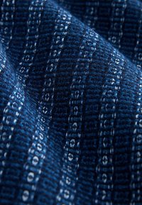 Geweven stof in donkerblauw met lichtere blauwe geometrische patronen, met een gestructureerd oppervlak en een gestructureerd weefpatroon.