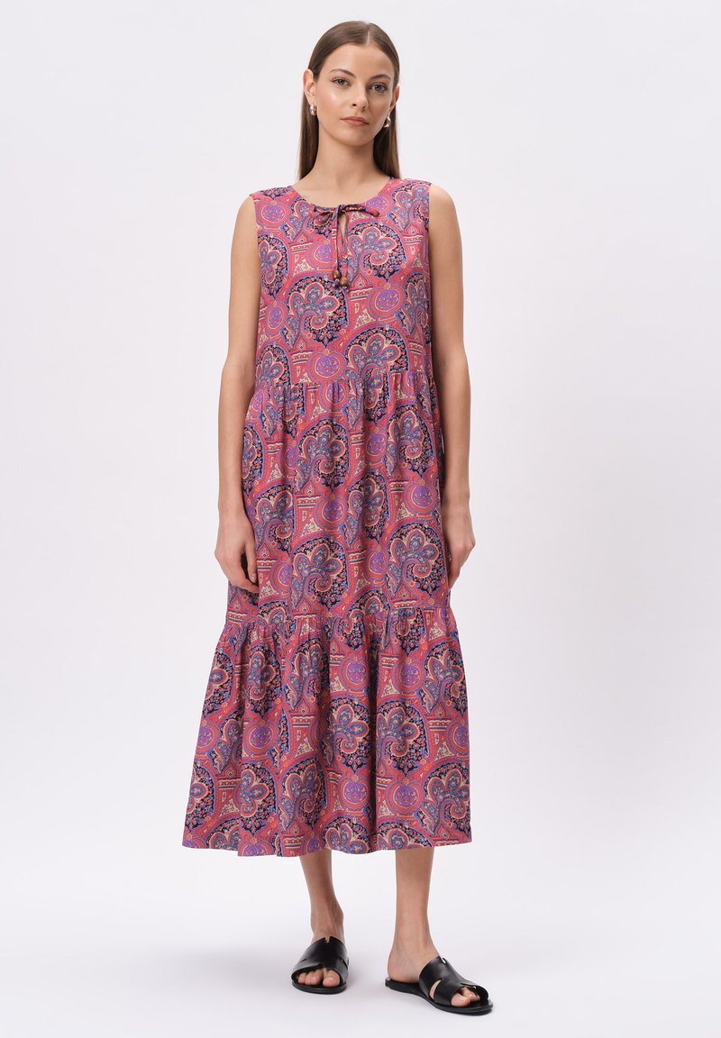 Beżowa sukienka midi bez rękawów z printem paisley, z okrągłym dekoltem i detalem wiązania. Luźny krój z falbaniastej spódnicy. Czarne sandały.