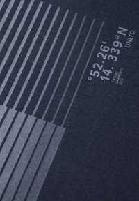 Tissu bleu marine avec des rayures verticales grises claires et le texte "52,26° N 14,339°" avec des coordonnées, affiché dans une police sans-serif moderne.