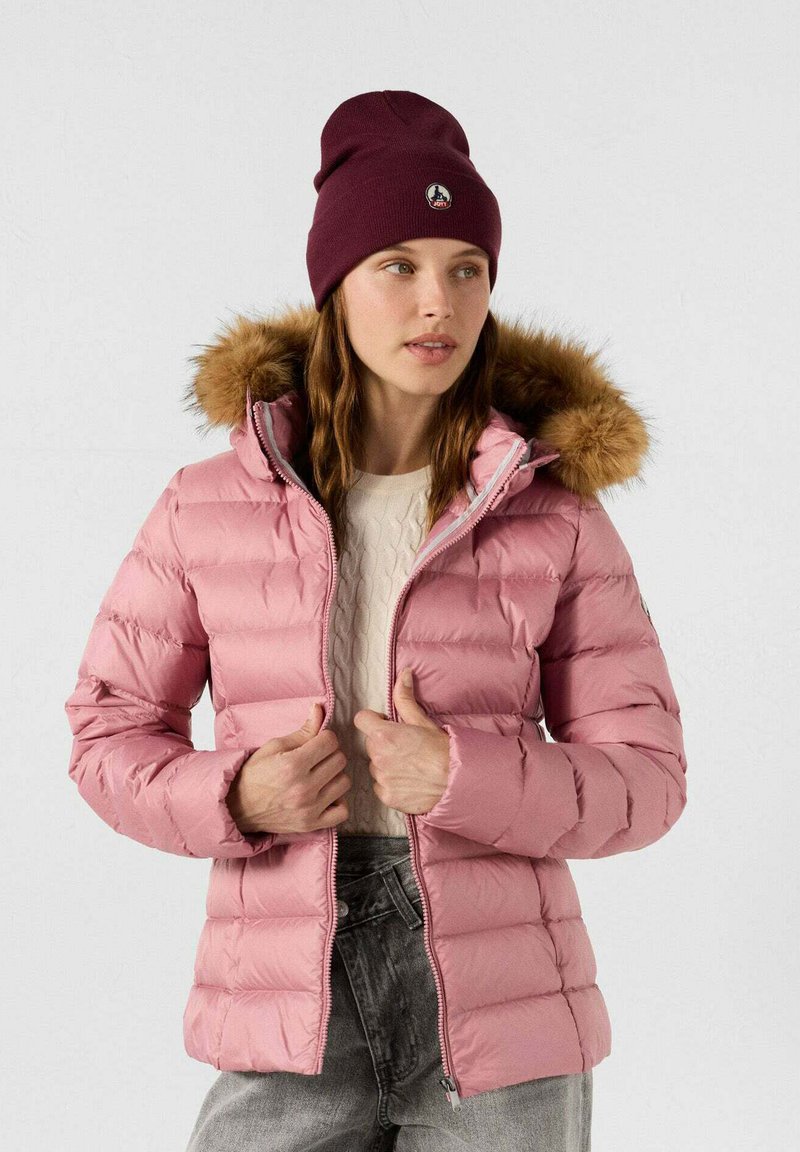 Giacca puffer rosa chiaro con cappuccio bordato di pelliccia, chiusura con zip e polsini a coste, abbinata a un berretto bordeaux e a un maglione strutturato.
