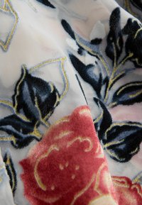 Tissu transparent avec broderie florale en velours bleu foncé, rouge, blanc et détails en fil doré.