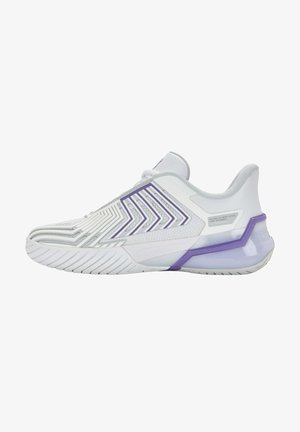 Chaussure de sport blanche avec des accents violets, dotée d'une tige texturée, d'un motif en zigzag et d'une semelle flexible pour l'adhérence et le soutien.