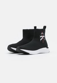 Czarne, dziergane, sięgające kostki trampki z białą podeszwą, z teksturowanym wzorem i akcentem z logo po bokach.