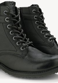 Musta nahast sidumiskingade paar, millel on külgsiibid ja tekstureeritud kummitaldad.