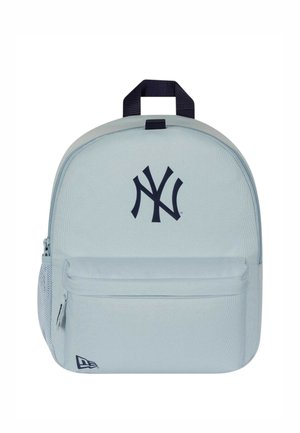 Lysegrå rygsæk med lynlåslomme foran, netlomme i siden, sort New York Yankees-logo og sort håndtag på toppen.