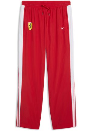 Czerwone spodnie dresowe z białymi paskami po bokach, elastycznym pasem ze sznurkiem, logo tarczy Ferrari na lewym udzie oraz logo Puma na prawym udzie.