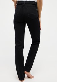 Pantalones vaqueros de denim negro con un diseño ajustado, piernas rectas, estilo de cinco bolsillos y costuras sutiles en los bolsillos traseros.