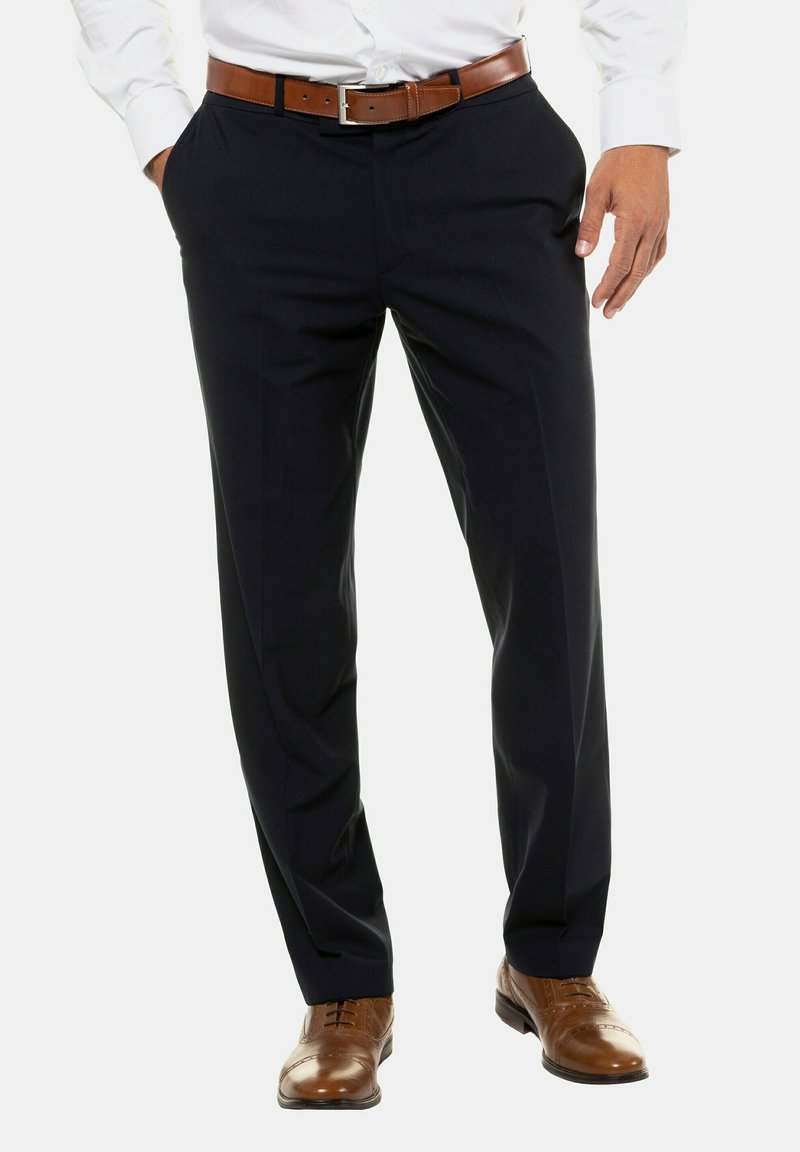 Pantaloni eleganti blu navy con una vestibilità su misura e una texture liscia, abbinati a una cintura in pelle marrone e scarpe stringate marroni.