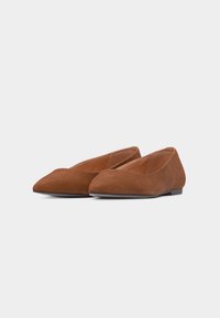 Paire de chaussures plates en daim marron à bout pointu avec talons bas sur un fond neutre.