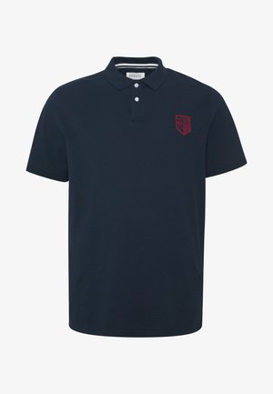 Tummansininen polo-paita, joka on valmistettu puuvillasta. Paidassa on kaksinappinen kaulus, lyhyet hihat ja vasemmassa rinnassa punainen brodeerattu logo.