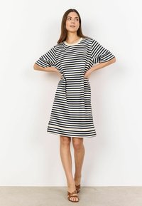 Striped dress in navy and cream with short sleeves, A-line shape, knee-length, featuring side pockets and a round neckline. Brown sandals.