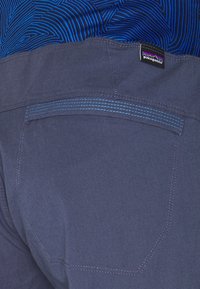 Mörkblå Patagonia-shorts med ett blått mönster på midjebandet, med en bakficka som har kontrasterande sömdetaljer.