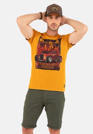 T-shirt en coton jaune avec un graphisme de hot rod avec des flammes, associé à un short en coton vert. Le texte indique "CRAZY HOT-ROD SINCE 1929."