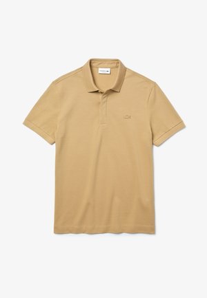 Lacoste beige polo-shirt i bomull. Den har en ribbad krage, en tre-knappluck och en ton-i-ton broderad logotyp på bröstet.