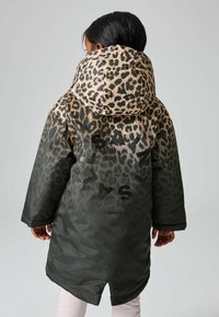 Leopardenmuster-Parka mit einer beigen Kapuze, dunkelgrünem Körper und großen schwarzen Buchstaben. Glattes Material mit leicht glänzender Oberfläche.