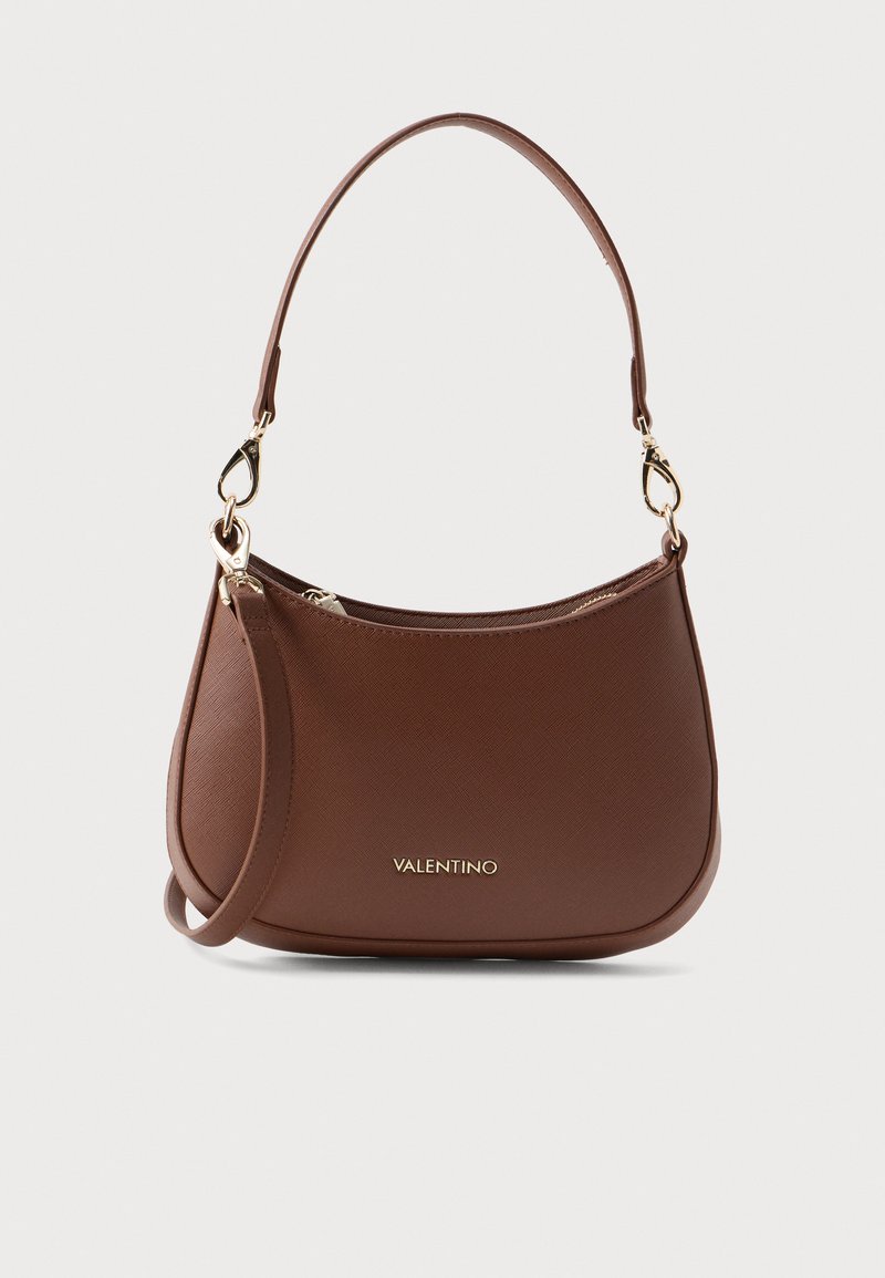 Bolsa de mão em couro castanho com um acabamento texturizado, forma curva, ferragens douradas e uma alça de ombro destacável. Possui fecho em zíper.