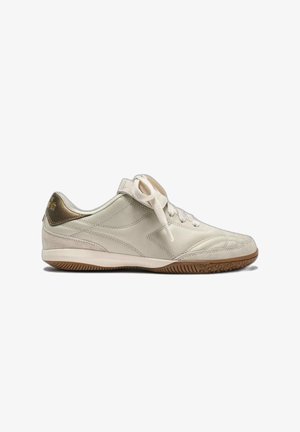 Weißer flacher Sneaker mit beiger Sohle und goldenem Fersendetail, mit Schnürsenkeln und seitlichem, gestepptem Design, von der Außenseite gezeigt.