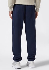 Pantalones de chándal azul marino con puños y cintura elástica. Hechos de una tela suave, presentan un corte holgado y no tienen patrones visibles ni detalles de hardware.
