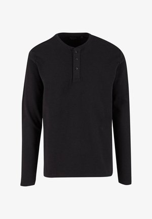 Camisa henley negra de manga larga hecha de algodón texturizado, con cuello redondo y tapeta de tres botones en la parte delantera.