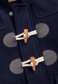 Marineblauer Wollmantel mit Holzknopfverschlüssen, beigem Seil und grauen Lederpatches. Beinhaltet strukturierten Stoff und praktische Designelemente.