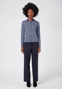 Navy patterned blouse with long sleeves and a collar, paired with navy wide-leg trousers. Black ankle boots complete the outfit.